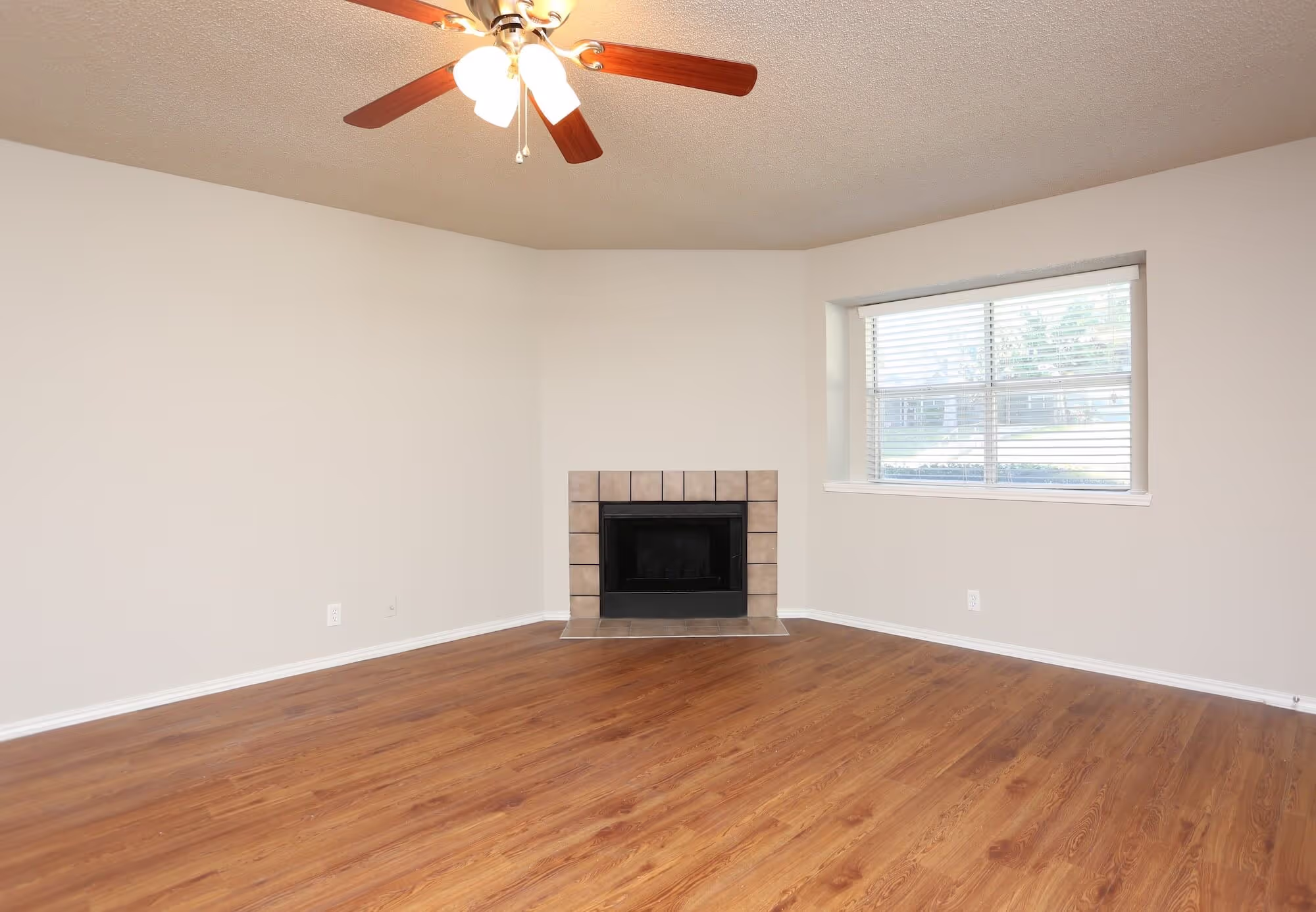 Living room with large window, fireplace, and ceiling fan.